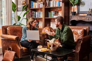 a man and woman sitting at a table with a laptop at R. Kipling by Happyculture in Paris