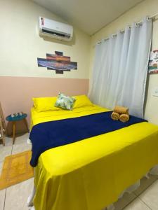 a bedroom with a bed with yellow and blue sheets at Casa Silveira NORONHA in Fernando de Noronha