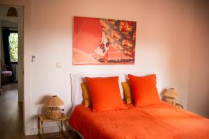 a bedroom with a bed with orange pillows and a painting at El botanico de Sagra in Sagra