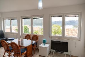 a living room with a table and chairs and windows at ENA Kuća za odmor in Ston