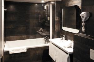 ein Badezimmer mit einer Badewanne, einem Waschbecken und einem Spiegel in der Unterkunft Best Western Allegro Nation in Paris