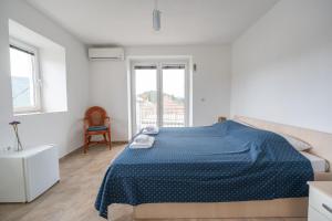 a white bedroom with a blue bed and a chair at ENA Kuća za odmor in Ston