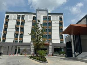 a large building with a tree in front of it at Remas Hotel Hatyai in Hat Yai