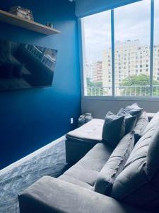 um quarto azul com um sofá em frente a uma janela em Conforto em Copacabana: 260m da Praia no Rio de Janeiro