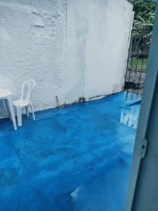 a white chair sitting on a patio with blue water at Suíte Lazuli in Itaparica Town