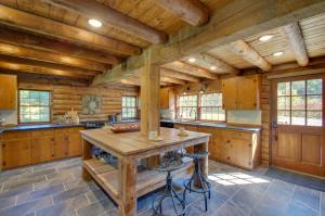 a large kitchen with wooden cabinets and a wooden table at Cozy Log Cabin Getaway with Fire Pit and 3 Acres! in Ruckersville