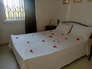 a white bed with red flowers on top of it at Beautiful apartment in secured residence close to beach in Trou aux Biches