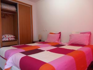 トロイアにあるCasa das Dunas Soltroiaのベッドルーム1室(ピンクと紫の枕が備わるカラフルなベッド1台付)