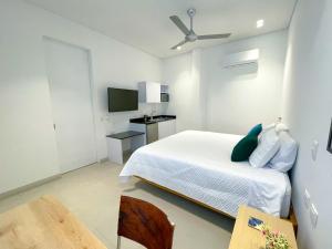 ein weißes Schlafzimmer mit einem Bett und einem TV in der Unterkunft Apartaestudio Brumilo 1 in Montería