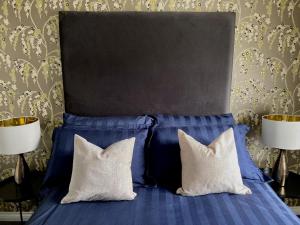 a blue bed with two white pillows and two lamps at Edward St Apartments in Belfast