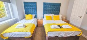 Dos camas individuales en una habitación con detalles en amarillo. en mySTAYINN Strathblane House, en Inverness