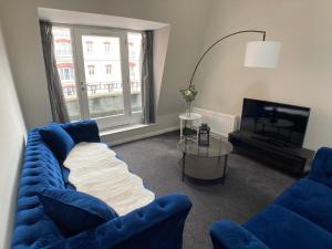 a living room with a blue couch and a tv at Edward St Apartments in Belfast