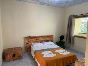 een slaapkamer met een bed met handdoeken erop bij Pousada Casinha Velha in Macacos
