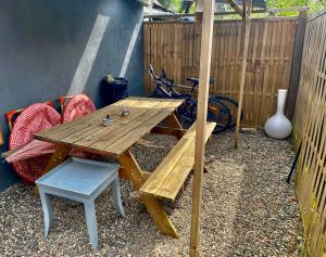 una mesa de picnic de madera y un banco y un jarrón en Petite maison au calme avec jardin clôturé les animaux bienvenue en Mollau