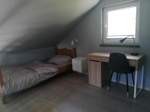 um quarto com uma cama, uma secretária e uma janela em Dom wypoczynkowy Pod kasztanem 1 em Wartkowo