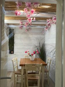 een houten tafel met stoelen en bloemen erop bij Vanessa Home in Burano