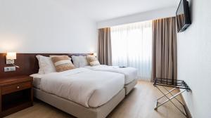 a hotel room with two beds and a television at Albergaria Quim Barreiros in Vila Praia de Âncora