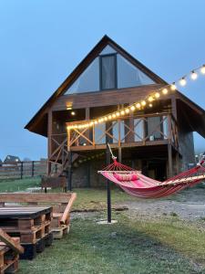 a hammock in front of a house with lights at Cottage Mtachy in Stepantsminda