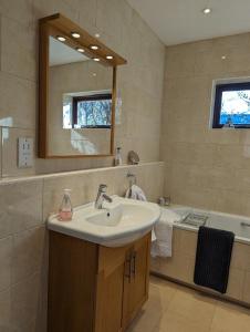 a bathroom with a sink and a mirror and a tub at Little Chilsbury in Potterne