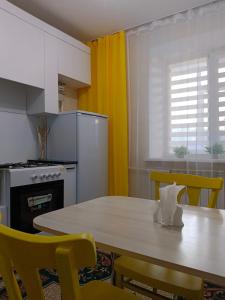 a kitchen with a table and yellow chairs at 12 Microragion Apartments in Aktobe
