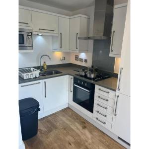 a kitchen with white cabinets and a sink and a stove at Spacious 1 Bedroom Flat in Kilburn Park F55 in London