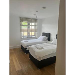 a bedroom with two beds and a window at Spacious 1 Bedroom Flat in Kilburn Park F55 in London