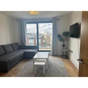 a living room with a couch and a table and a window at Spacious 1 Bedroom Flat in Kilburn Park F55 in London