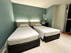 1 dormitorio con 2 camas y pared azul en De UPTOWN Hotel @ SS2, en Petaling Jaya