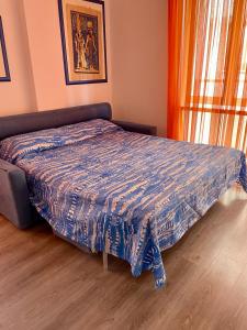 a bed with a blue comforter in a bedroom at Appartamento Lignano Sabbiadoro Centro in Lignano Sabbiadoro