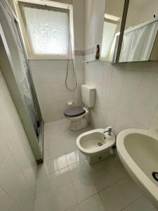 a white bathroom with a toilet and a sink at Appartamento Lignano Sabbiadoro Centro in Lignano Sabbiadoro +18 photos