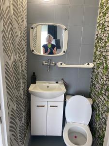 a woman taking a picture of a bathroom with a toilet and sink at ADA - pokoje gościnne in Łeba