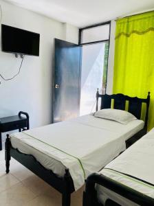 2 camas en una habitación con ventana y TV en HOTEL MAR Y MAR, en Santa Marta