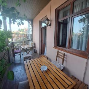 a porch with a wooden table and chairs on a balcony at Luca in Tbilisi City