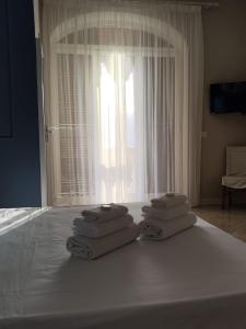 einen Haufen Handtücher auf einem Bett mit Fenster in der Unterkunft Villa Antonietta Ischia in Ischia