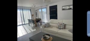 uma sala de estar com um sofá branco e uma mesa em Cœur de provence em Gréoux-les-Bains