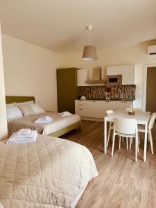 1 dormitorio con 2 camas, mesa y cocina en Fresia B&B, en Tuscania