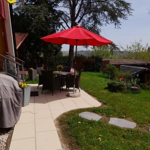 une table avec un parapluie rouge dans une cour dans l'établissement Eifeler Finnhaus mit Sauna, à Dockweiler