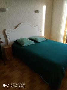 a bed with a white headboard and two green pillows at Appartement de montagne à La LLagonne in La Llagonne