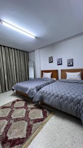 een slaapkamer met 2 bedden en een tapijt bij Chez-moi in Sfax