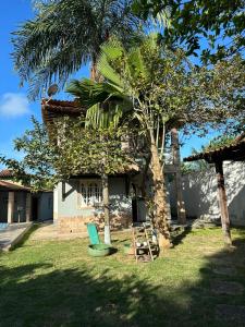 a house with a palm tree and a chair in the yard at Casa inteira Labirinto in Saquarema