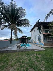 a palm tree next to a house with a pool at Casa inteira Labirinto in Saquarema