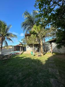 a yard with a house with a picnic table and palm trees at Suíte Labirinto 01 in Saquarema