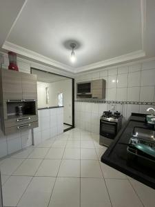 a large kitchen with white tiled floors and appliances at Suíte Labirinto 01 in Saquarema