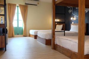 a bedroom with two beds and a large window at Siri Poshtel Bangkok in Bangkok