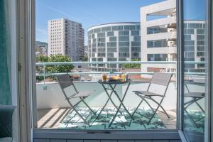 einen Tisch und Stühle auf einem Balkon mit Stadtblick in der Unterkunft L'Amadéo - T2 Centre-ville & Parking in Clermont-Ferrand