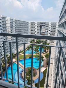 een balkon met uitzicht op het zwembad van een appartement bij Shell Residences condotel Staycation in Manilla