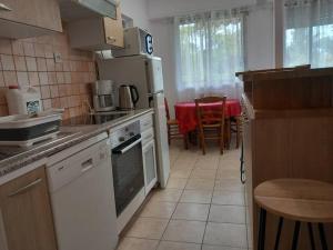 a kitchen with white appliances and a table with chairs at Les dunes de Nauzan in Vaux-sur-Mer