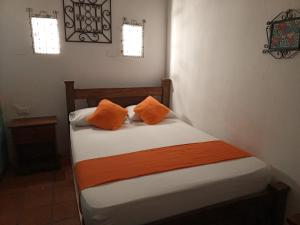 Una cama pequeña con dos almohadas naranjas. en Hotel Viajero Mompox en Mompos
