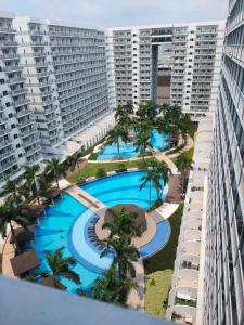 een uitzicht over een groot zwembad met palmbomen en gebouwen bij Shell Residences condotel Staycation in Manilla