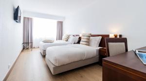 ヴィーラ・プライア・デ・アンコラにあるAlbergaria Quim Barreirosのベッド2台とソファが備わるホテルルームです。